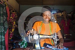 A young african female tailor smiling while working with her sewing machine