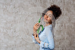 Young African girl in a blue dress with a Tulip on a gray background. The concept of women`s day and spring