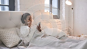 Young African Girl Celebrating Success while Using Smartphone in Bed