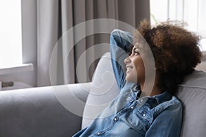 Young African girl rest leaned on couch staring into distance