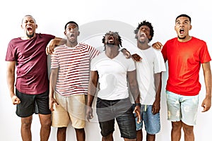 Young african group of friends standing together over isolated background angry and mad screaming frustrated and furious, shouting
