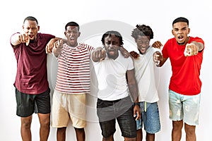 Young african group of friends standing together over isolated background pointing displeased and frustrated to the camera, angry