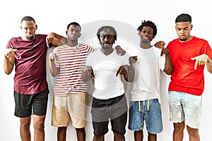 Young african group of friends standing together over isolated background pointing down looking sad and upset, indicating