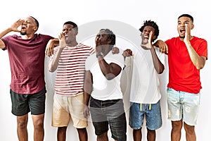 Young african group of friends standing together over isolated background shouting and screaming loud to side with hand on mouth
