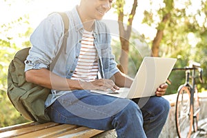 Young african guy in park outdoors using laptop computer