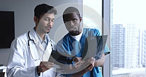 Young African and Indian male radiologists examining x-ray