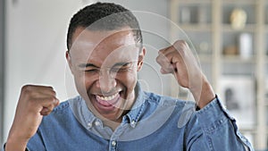 Young African Man Celebrating Success Gesture in Office