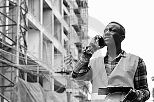 Young African man construction worker talking on the phone at building site