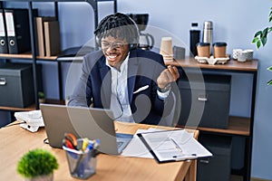 Young african man with dreadlocks working at the office wearing headset screaming proud, celebrating victory and success very
