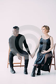 Young african man and his caucasian pregnant woman sit on chairs