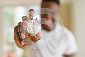 Young african man holding silver retro stopwatch counting time