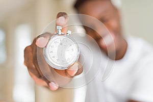 Young african man holding silver retro stopwatch counting time