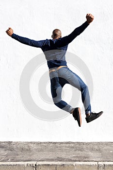 Young african man jumping in air on sidewalk outdoors