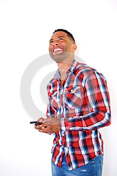Young african man laughing with mobile phone and looking up