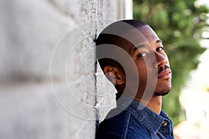 Young african man leaning against wall