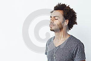 Young african man listening to music in headphones with closed eyes. Copy space.