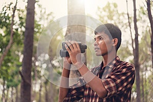 Young African man looking through binocular in the forest, Travel concept.