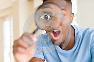 Young african man looking through magnifying glass