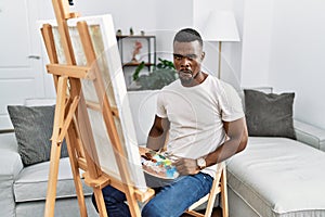 Young african man painting on canvas at home depressed and worry for distress, crying angry and afraid