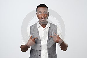 Young african man pointing at himself, making excuses or verbally defending,