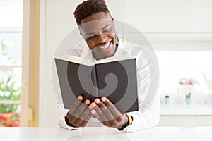 Young african man reading a book, studying for univeristy smiling confident photo