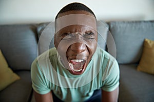 Young African man screaming in anguish at home photo