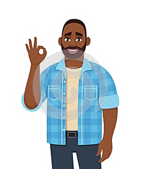 Young African man showing okay, cool gesture sign with fingers. Trendy happy looking black person making OK, good symbol.