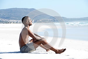 Young african man sitting alone on the beach