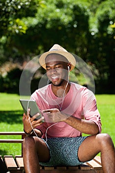 Young african man sitting outdoors with a digital tablet