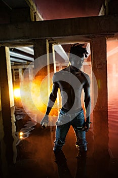 Young African man stands under bridge and holds colored red smoke bomb