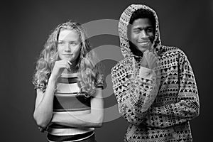 Young African man with teenage girl together against gray background