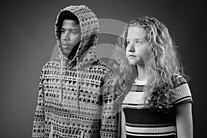 Young African man with teenage girl together against gray background