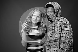 Young African man with teenage girl together against gray background