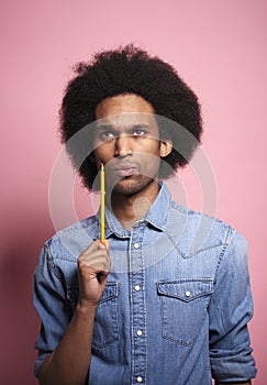 Young African man thinking something with a pencil in hand