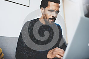 Young African man using laptop while sitting at his modern coworking place.Concept of full concentration.Blurred