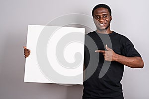 Young African man wearing black shirt against gray background