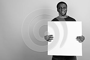 Young African man wearing black shirt against gray background