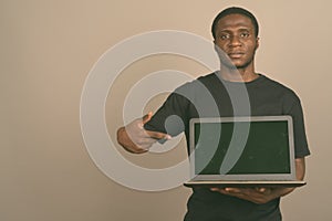 Young African man wearing black shirt against gray background