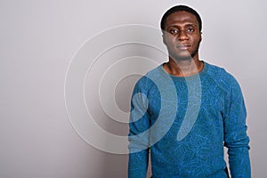 Young African man wearing blue long sleeved shirt against gray b