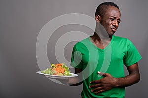 Young African man wearing green shirt against gray background