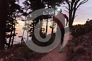 Young African man wearing a headlamp running at dusk