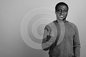 Young African man wearing long sleeved shirt against gray background
