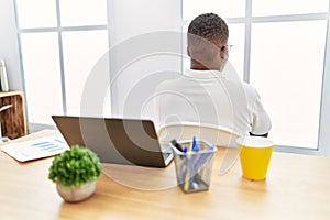 Young african man working at the office using computer laptop standing backwards looking away with crossed arms