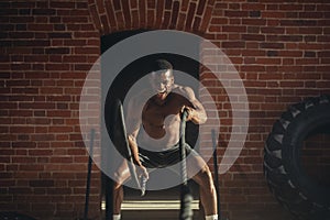 Young african man working out with battle ropes at a gym