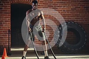 Young african man working out with battle ropes at a gym
