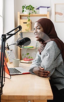 Young african muslim woman recording radio podcast from home studio photo