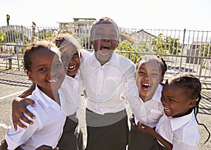 Young African schoolgirls in playground smiling to camera