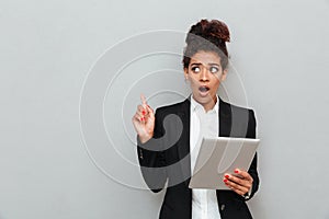 Young african shocked business woman over grey wall