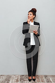 Young african thinking business woman over grey wall