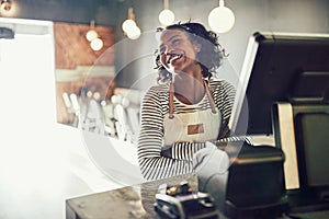 Young African waitress standing at an order terminal and laughin